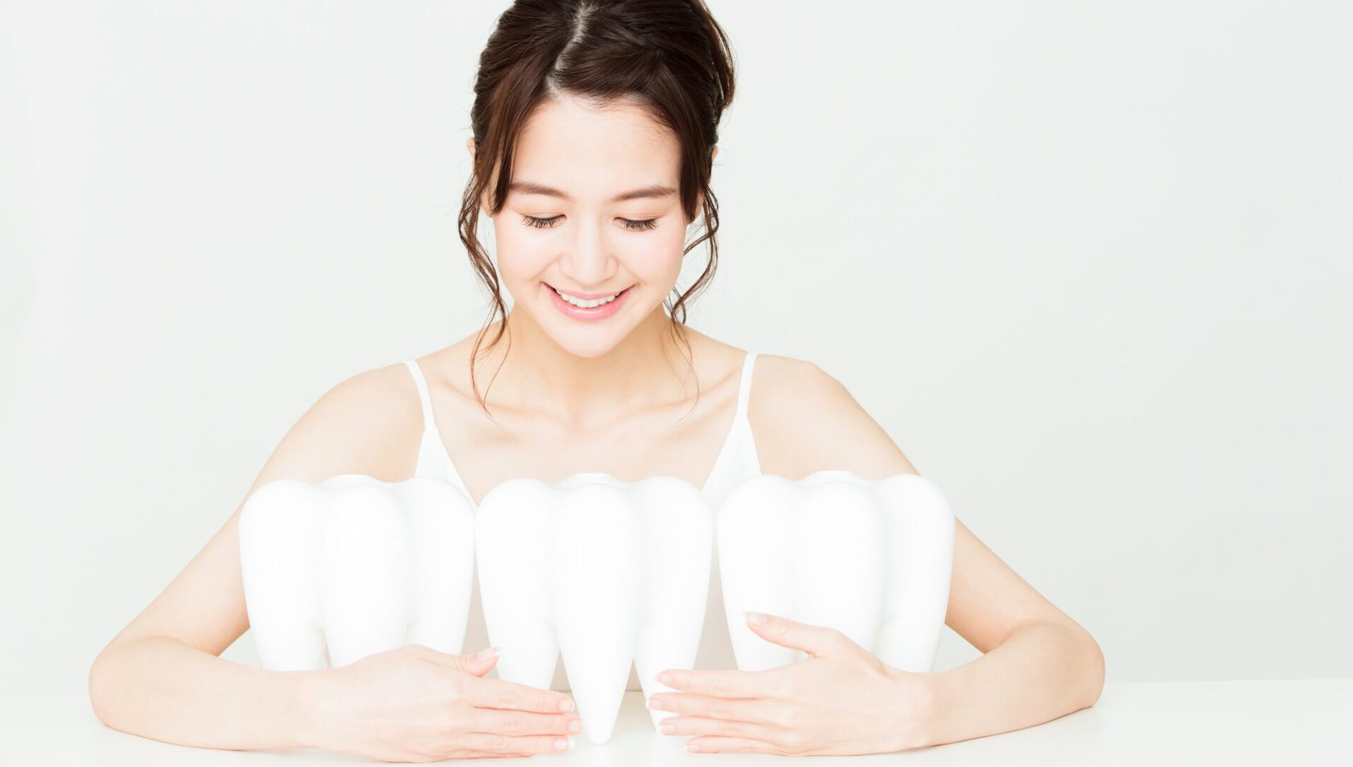 歯の模型を抱える女性の画像｜全身の健康を左右する「口腔内細菌」とは｜歯科医師会田の噛み合わせメディア-カムシル